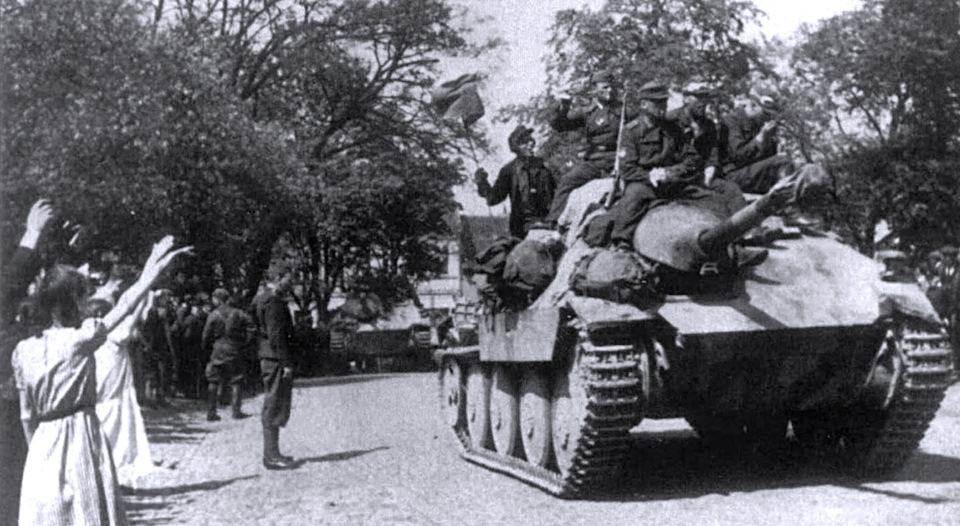 Прага приветствует освободителей. Власовцы на лёгкой самоходке Jagdpanzer 38(t) Škoda (Hetzer) с 75‑мм пушкой Рак 39/2, приписанной немцами к 1-й дивизии в 1945 году, въезжают в город. — ГАЗ Соболь 4х4